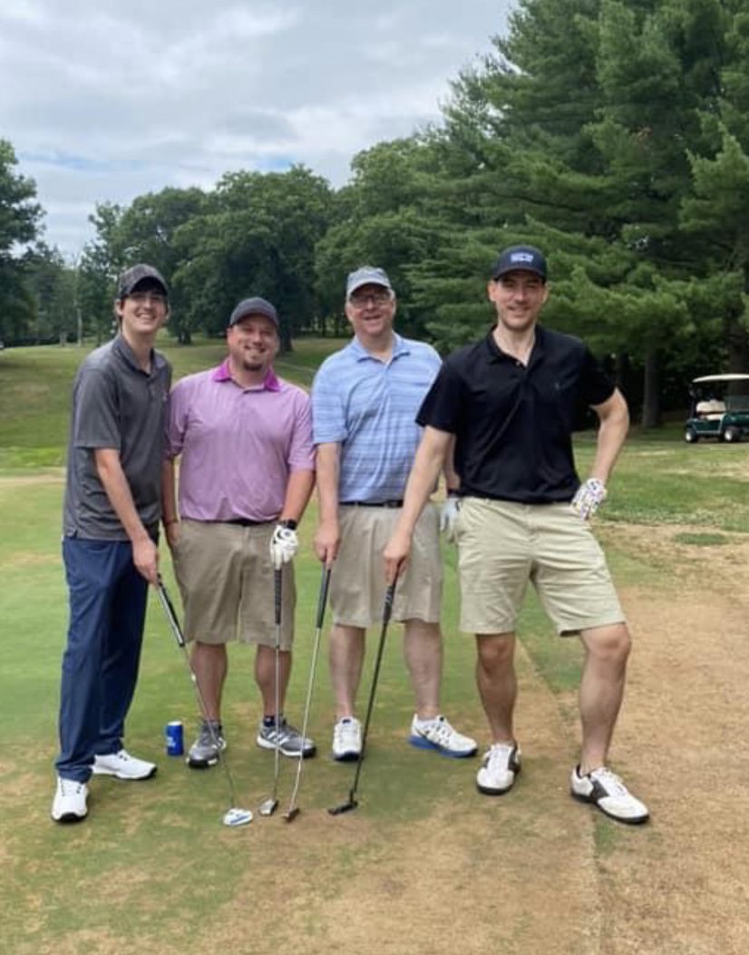 Four men are standing on a golf course.