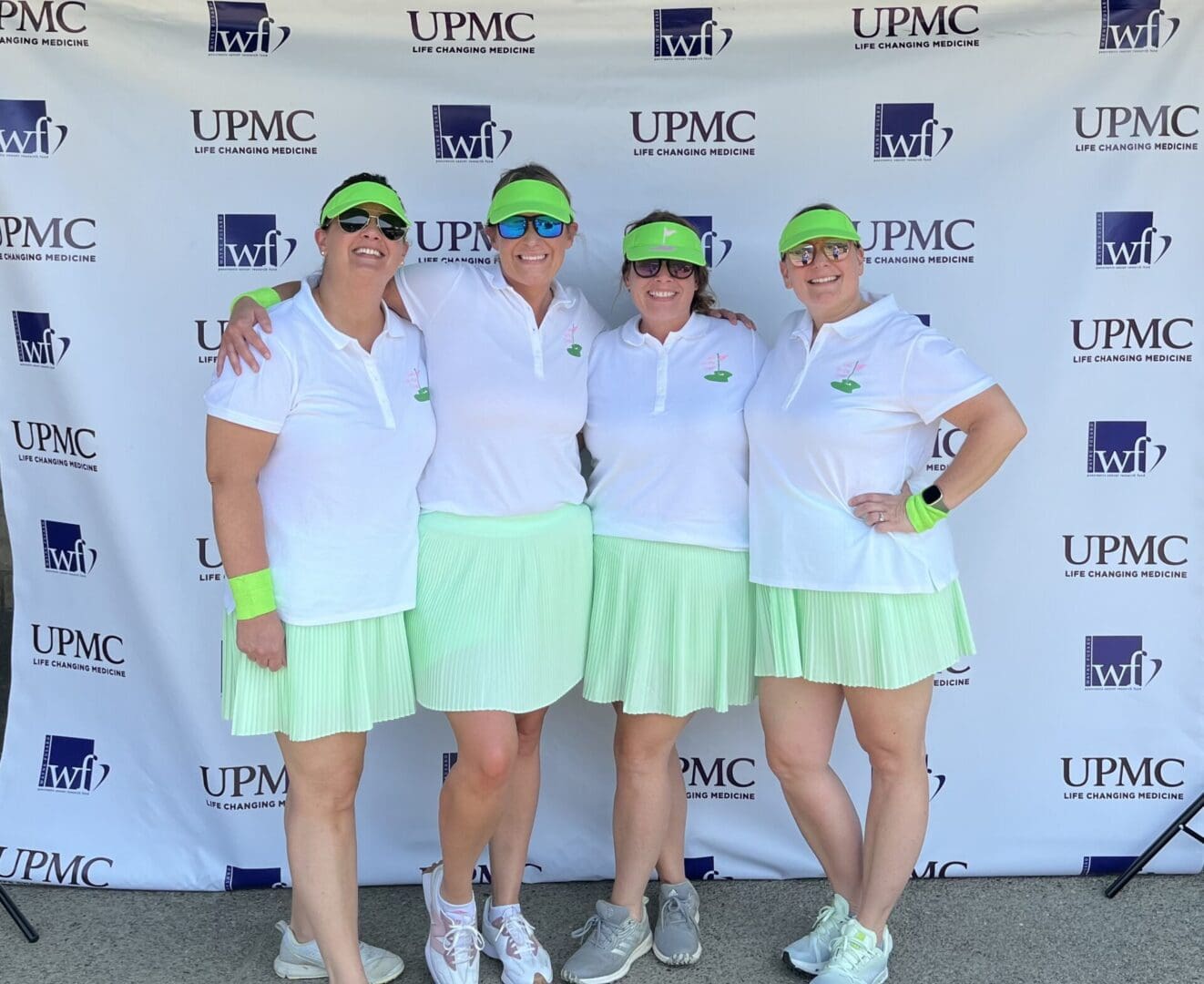 Four women in tennis outfits posing for a picture.