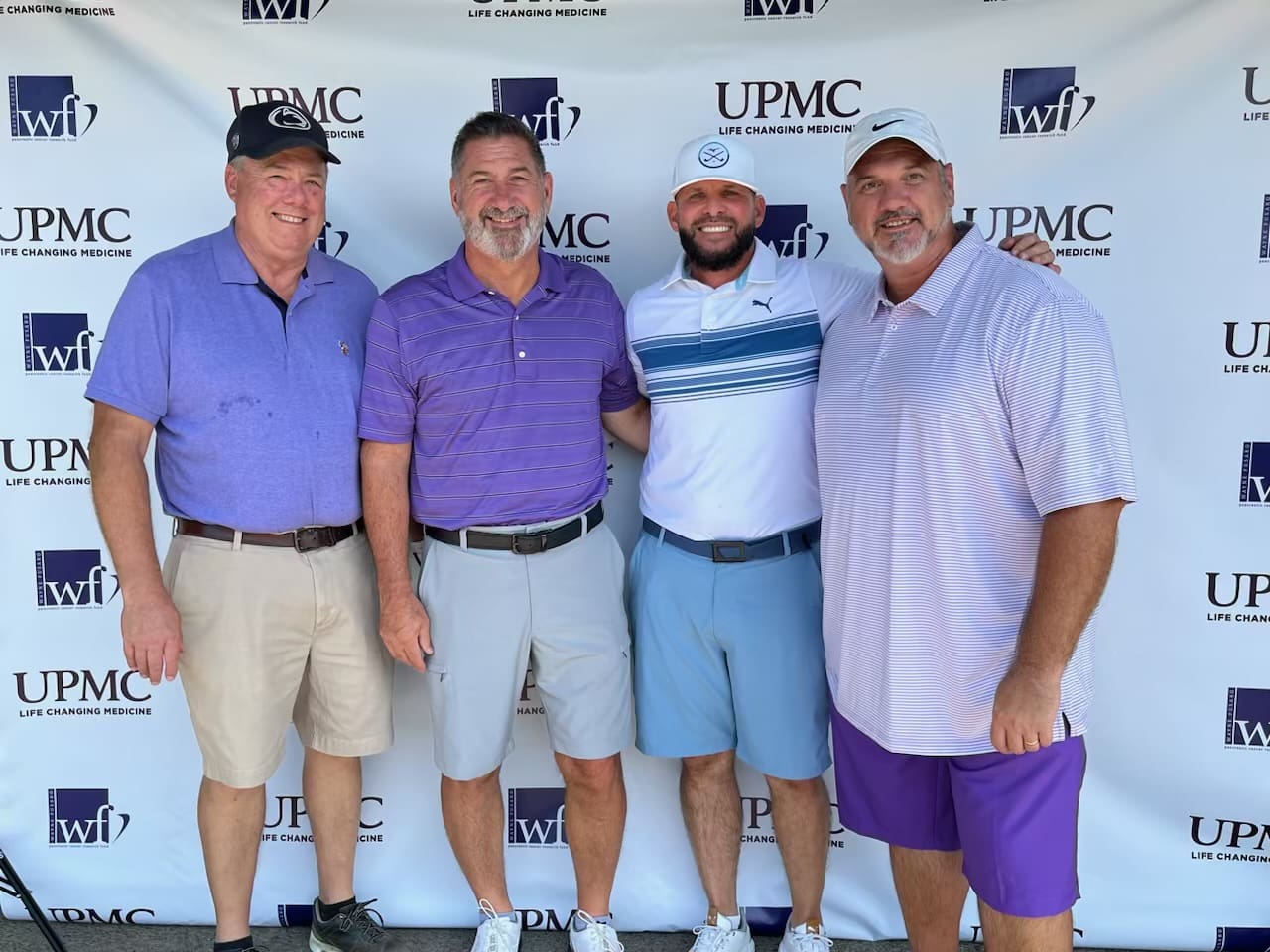 Four men standing in front of a wall with upmc logo.